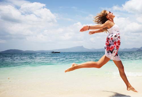 young woman running on beach with arms back